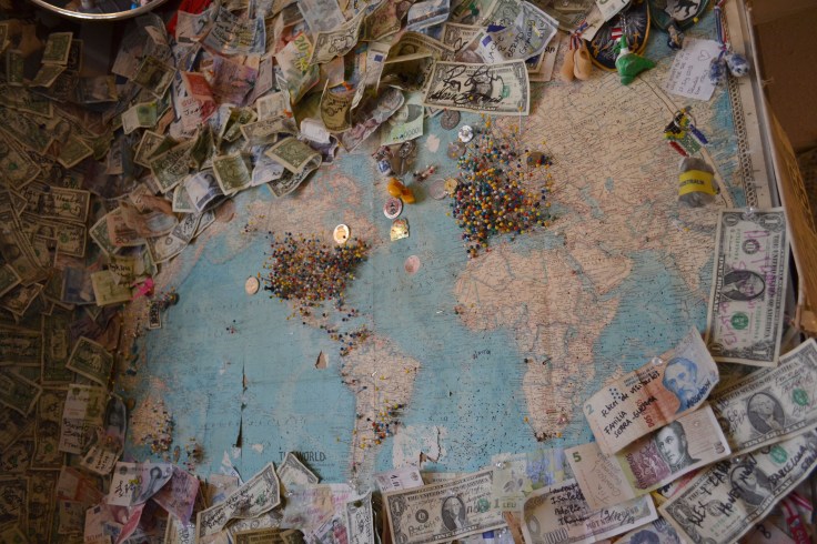 A world map with visitor pins and signed dollar bills in the Hackberry General Store. 